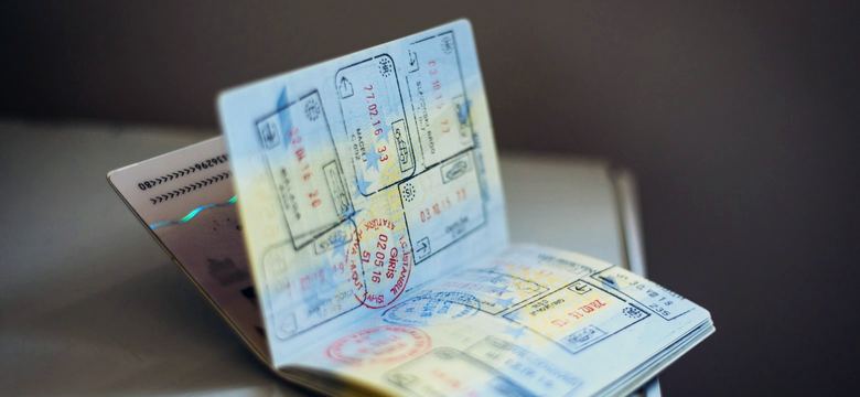 An open passport with numerous ink stamps on the pages on a table