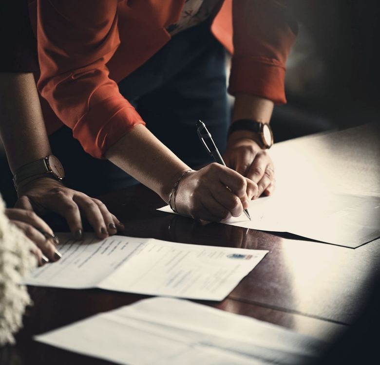 Person in orange long sleeve shirt writing on white paper